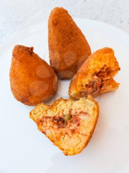 travel to Italy, italian cuisine - traditional arancini ( fried rice filled balls with filling coated with breadcrumbs) on white plate in Sicily