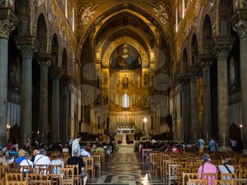 MONREALE, ITALY - JUNE 25, 2011: tourists indoor of Duomo di Monreale in Sicily. The cathedral of Monreale is one of the greatest examples of Norman architecture, it was begun in 1174