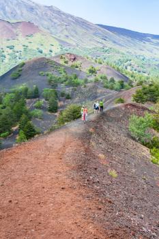 ETNA, ITALY - JULY 1, 2011 - tourists walk on path between old craters of Etna mount. Mount Etna is active volcano on the east coast of Sicily, the tallest active volcano in Europe