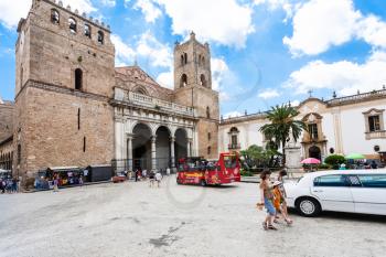 MONREALE, ITALY - JUNE 25, 2011: tourists and bus on square of Duomo di Monreale town in Sicily. The cathedral of Monreale is one of the greatest examples of Norman architecture, it was begun in 1174
