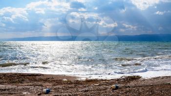 Travel to Middle East country Kingdom of Jordan - dirty beach of Dead Sea in cloudy winter day