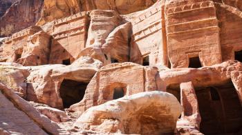 Travel to Middle East country Kingdom of Jordan - facades of ancient tombs and houses on Street of Facades in Petra town in winter