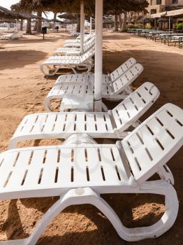 Travel to Middle East country Kingdom of Jordan - empty loungers Coral beach of Red Sea in Aqaba city in winter