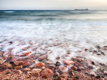 Travel to Middle East country Kingdom of Jordan - coastline of Gulf of Aqaba on Red Sea in winter evening (long exposure and focus on the sand in the foreground)