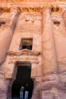 PETRA, JORDAN - FEBRUARY 21, 2012: tourists in door of Royal Urn Tomb in ancient Petra town. Rock-cut town Petra was established about 312 BC as the capital city of the Arab Nabataean