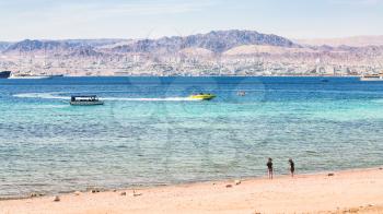 AQABA, JORDAN - FEBRUARY 23, 2012: sand beach of Aqaba city and view of Eilat city in background in winter. Jordan country has only one exit to sea in Gulf of Aqaba, the length of the coast is 27 km