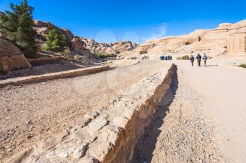 PETRA, JORDAN - FEBRUARY 21, 2012: tourists walk to Petra town in Bab as-Siq area in winter. Rock-cut town Petra was established about 312 BC as the capital city of the Arab Nabataean