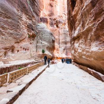 PETRA, JORDAN - FEBRUARY 21, 2012: people near niches in Al Siq gorge to ancient Petra town in winter. Rock-cut town Petra was established about 312 BC as the capital city of the Arab Nabataean