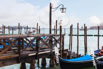 travel to Italy - Gulls on pier and gondolas in Venetian lagoon in spring
