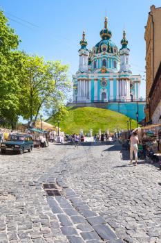 KIEV, UKRAINE - MAY 6, 2017: people on market on Andriyivskyy Descent and view of St Andrew's Church in Kiev city in spring. The church was constructed in 1747-1754 by architect Bartolomeo Rastrelli