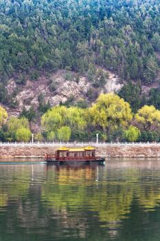 travel to China - view of boat in Yi river and green East Hill of Longmen grottoes area in spring season