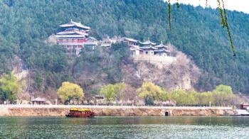travel to China - view of memorial on East Hill of Chinese Buddhist monument Longmen Grottoes (Dragon's Gate Grottoes, Longmen Caves) through Yi river in spring season