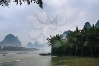 travel to China - passenger boads in mist over river near Xingping town in Yangshuo county in spring morning