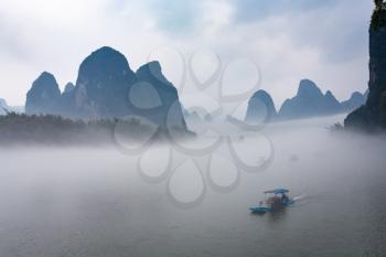 travel to China - view of fog with ships on river near Xingping town in Yangshuo county in spring morning