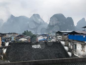 travel to China - view of wet roofs of Yangshuo Town and karst mountain peaks in Yangshuo County in spring evening