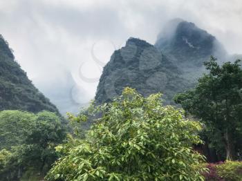 travel to China - gray clouds over green karst mountains in Yangshuo County in spring season