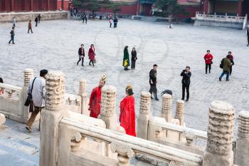 BEIJING, CHINA - MARCH 19, 2017: couple in red dresses and people on courtyard of Imperial Ancestral Temple (Taimiao, Working People's Cultural Palace) in Beijing Imperial city in spring
