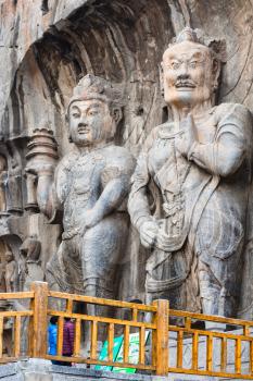 LUOYANG, CHINA - MARCH 20, 2017: visitors near Buddhist sculptures in the main Longmen Grotto (Longmen Caves). The complex was inscribed upon the UNESCO World Heritage List in 2000