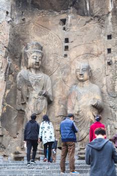 LUOYANG, CHINA - MARCH 20, 2017: tourists near Buddhist sculptures in the main Longmen Grotto (Longmen Caves). The complex was inscribed upon the UNESCO World Heritage List in 2000