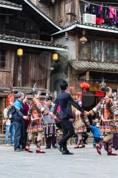 CHENGYANG, CHINA - MARCH 27, 2017: tourists and dong people in round dance on square of Folk Custom Centre during Culture Show in Chengyang village. Chengyang includes eight villages of Dong people