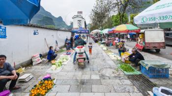 YANGSHUO, CHINA - MARCH 30, 2017: people on outdoor garden market on street in Yangshuo in spring. Town is resort destination for domestic and foreign tourists because of scenic karst peaks
