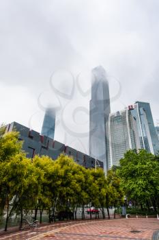 GUANGZHOU, CHINA - MARCH 31, 2017: fog over towers on quay in Zhujiang New Town of Guangzhou city in spring rainy day. Guangzhou is the third most-populous city in China with population about 13,5 mln
