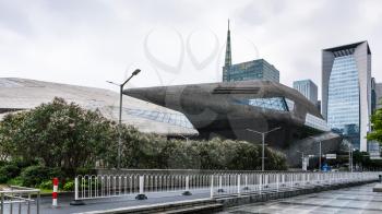 GUANGZHOU, CHINA - MARCH 31, 2017: street and side view of Opera House in Zhujiang New Town of Guangzhou city in spring rain. Theater was designed by Zaha Hadid, and opened in 2010.