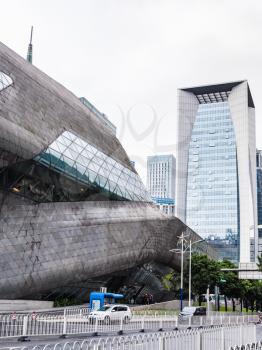 GUANGZHOU, CHINA - MARCH 31, 2017: wall of Opera House and modern houses in Zhujiang New Town of Guangzhou city in spring. Theater was designed by Zaha Hadid, and opened in 2010.