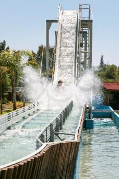 tourists in boat on water slide attraction in summer day