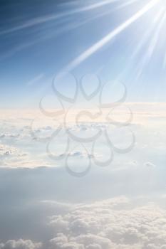 View from the airplane - sunbeams in blue sky over white clouds on mountains in Greece in autumn