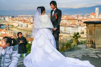 FLORENCE, ITALY - JANUARY 8, 2016: groom and bride during wedding ceremony on Piazzale Michelangelo in Florence city in sunny winter day. Piazzale Michelangelo is very popular viewpoint over town