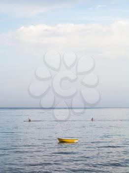 travel to Sicily, Italy - yellow boat and canoes in Ionian sea near waterfront in Giardini Naxos town in summer evening