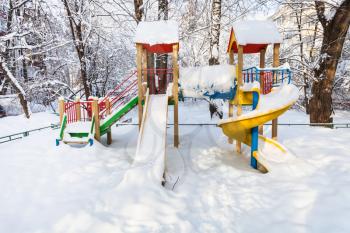 snow-covered public children playground at residential district in Moscow city in winter morning