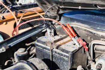 Jump start a flat car battery with another vehicle and jumper leads outdoor