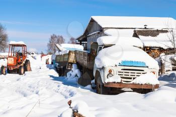 snow-covered transport on street in russian village Kikino in Smolensk Oblast of Russia in sunny winter day