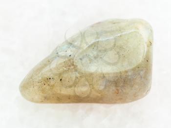 macro shooting of natural mineral rock specimen - polished labradorite gemstone on white marble background