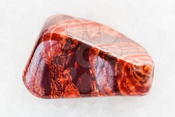 macro shooting of natural mineral rock specimen - polished Brecciated red jasper gemstone on white marble background
