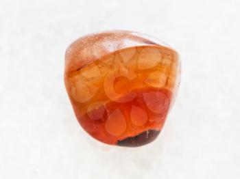 macro shooting of natural mineral rock specimen - polished carnelian gem stone on white marble background