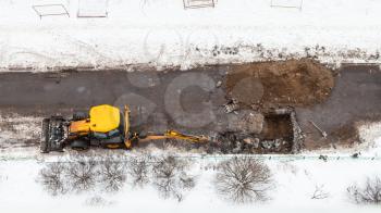 top view of excavator digging road to change sewer pipes in winter in Moscow city