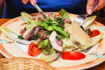 travel to France - visitor eats salad with typical local Norman meat appetizers in restaurant in Etretat town in Normandy