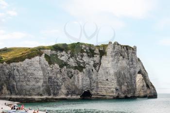 trave to France - people on beach near chalk cliff in Etretat town in Pays de Caux area of English Channel in summer