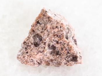 macro shooting of natural mineral rock specimen - rough Granite stone on white marble background