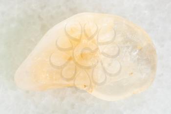 macro shooting of natural mineral rock specimen - tumbled yellow Citrine gemstone on white marble background
