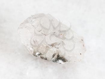 macro shooting of natural mineral rock specimen - raw rock-crystal of quartz gemstone on white marble background