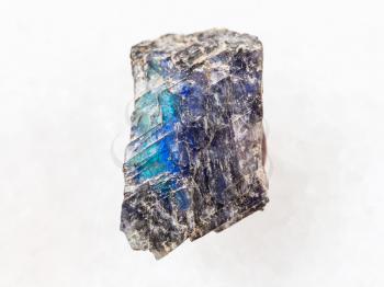 macro shooting of natural mineral rock specimen - rough labradorite stone on white marble background from Finland