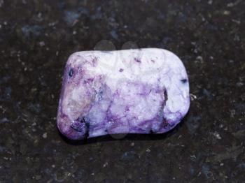 macro shooting of natural mineral rock specimen - polished Amethyst gemstone on dark granite background from Brazil