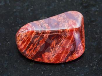 macro shooting of natural mineral rock specimen - polished Brecciated red jasper gemstone on dark granite background