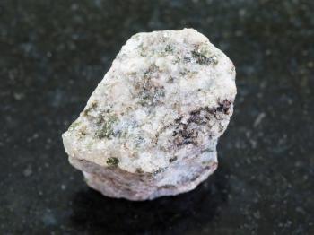 macro shooting of natural mineral rock specimen - rough Apatite ( ore of phosphorus) stone on dark granite background