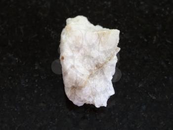 macro shooting of natural mineral rock specimen - scheelite vein (tungsten ore) in raw stone on dark granite background