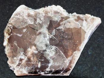 macro shooting of natural mineral rock specimen - rough brown mica lamina on dark granite background